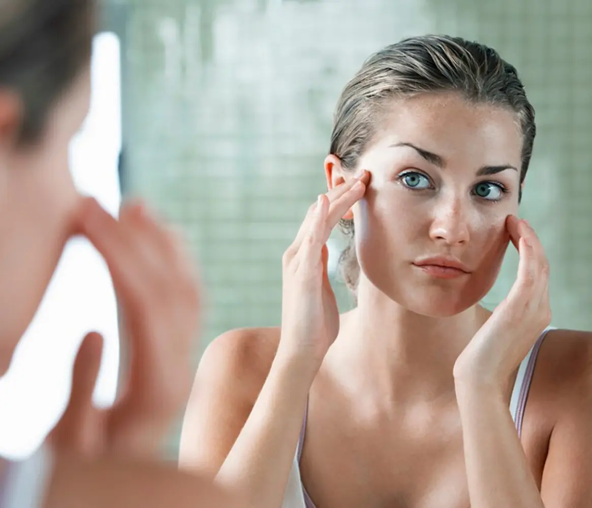 Woman examining her face in the mirror, illustrating the rejuvenating effects of Restylane injections in Brooklyn at KHROM MEDSPA & WELLNESS